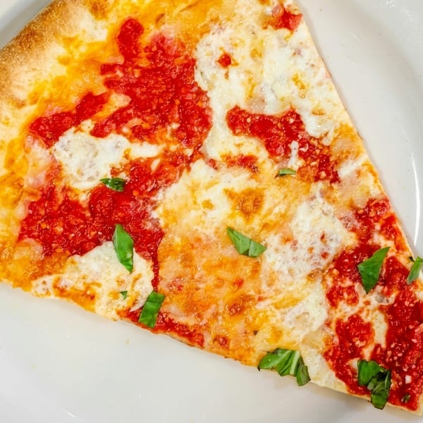A single slice of cheese pizza with red sauce and basil on a white plate.