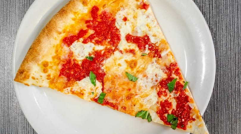 A single slice of cheese pizza with red sauce and basil on a white plate.