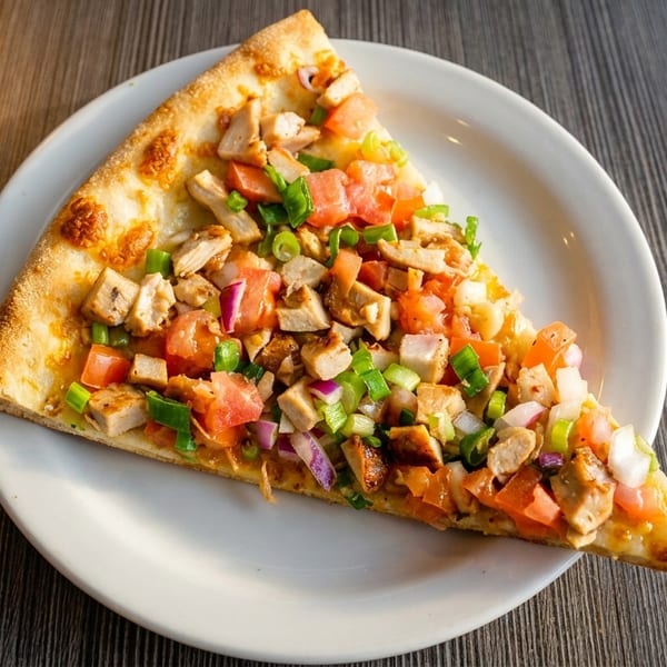 A single slice of chicken pizza with diced tomatoes, red onions, and green onions on a white plate.
